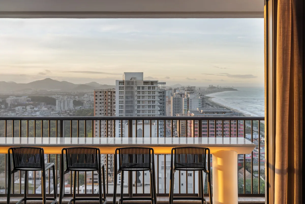 Sacada com bancada e cadeiras de frente para vista panorâmica da cidade e mar - Apartamento em Balne